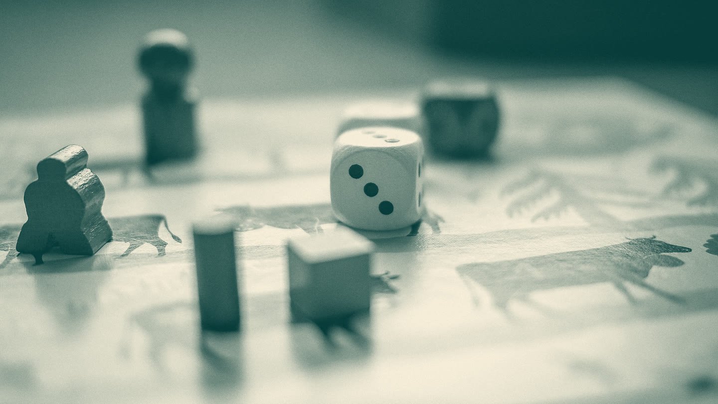Wooden pawns, a die and blocks standing on a printed game board, in close-up.