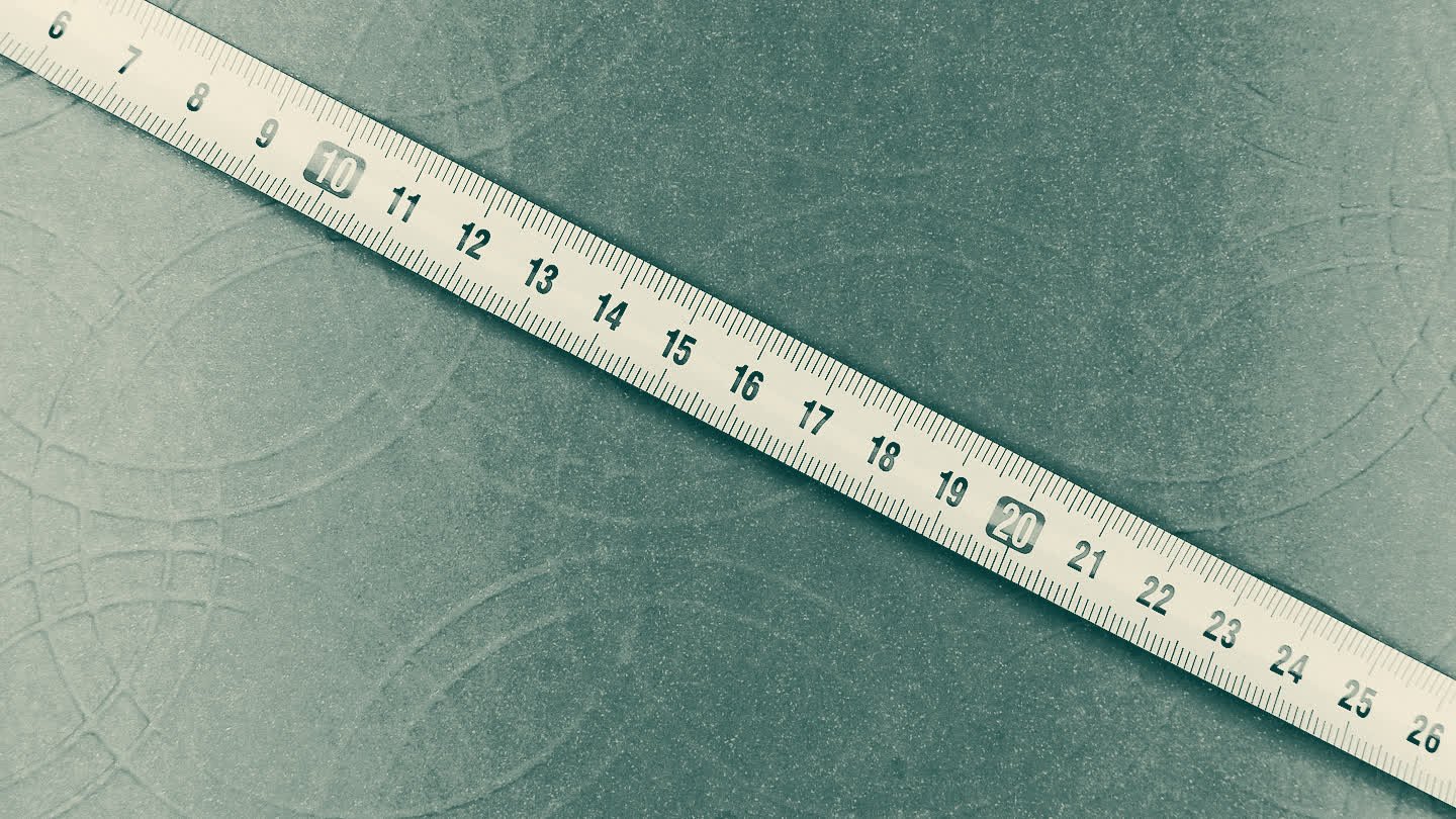 A tape measure laid diagonally across a textured surface, its marks running from 6 to 26.